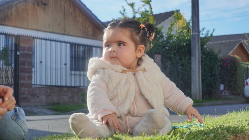 A cute baby sits in the sun.