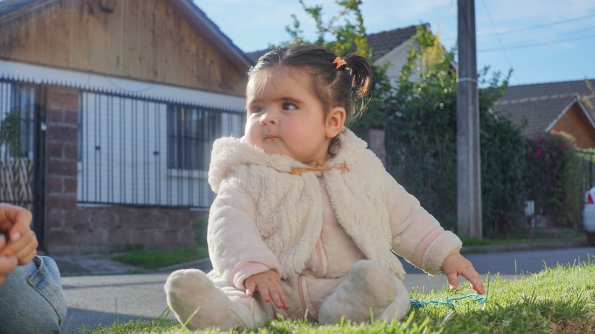 A cute baby sits in the sun.
